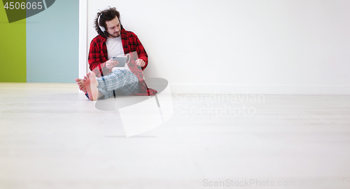 Image of young man listenig music on tablet at home