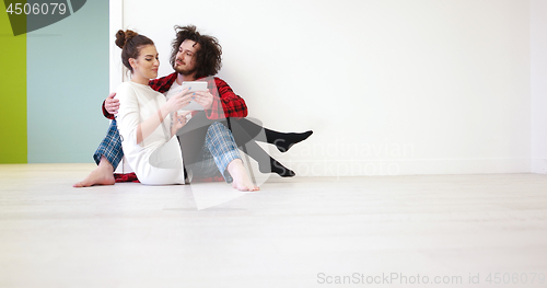 Image of Young Couple using digital tablet on the floor