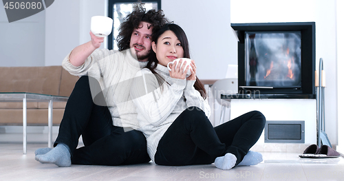 Image of multiethnic romantic couple  in front of fireplace