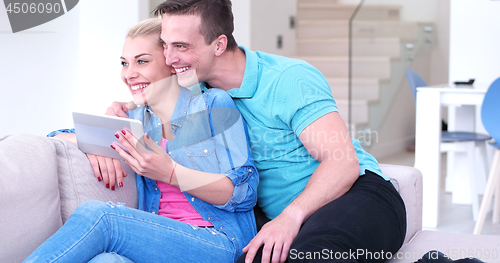Image of couple relaxing at  home with tablet computers