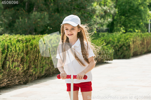 Image of Preschooler girl riding scooter outdoors.