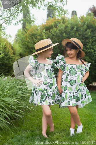 Image of Portrait of smiling beautiful girls with hats against green grass at summer park.