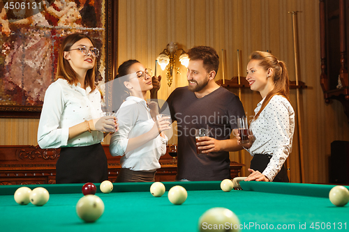 Image of Young men and women playing billiards at office after work.