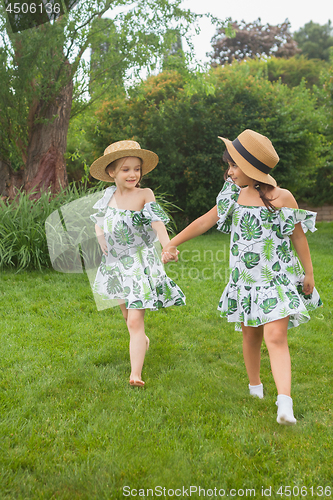 Image of Portrait of smiling beautiful girls with hats against green grass at summer park.