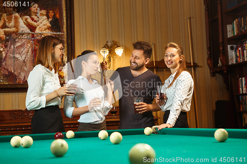 Image of Young men and women playing billiards at office after work.