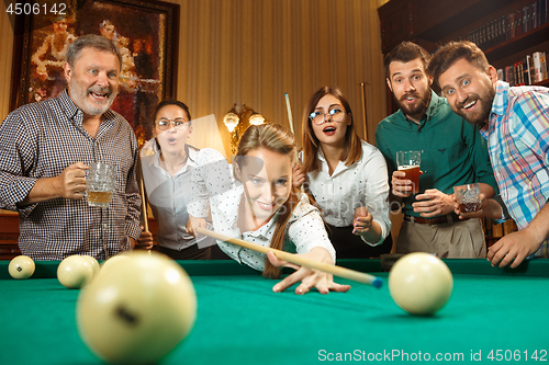 Image of Young men and women playing billiards at office after work.