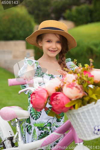 Image of Beautiful little girl riding a bicycle through the park. Nature, lifestyle