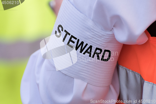 Image of Detail of an armband with text \"STEWARD\"