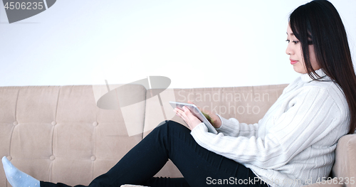 Image of asian woman using Digital Tablet on sofa