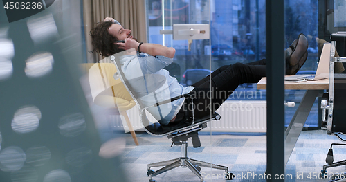 Image of businessman sitting with legs on desk