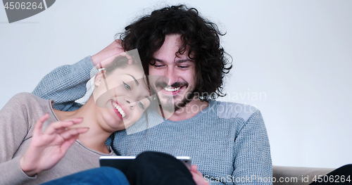 Image of couple relaxing at  home with tablet computers
