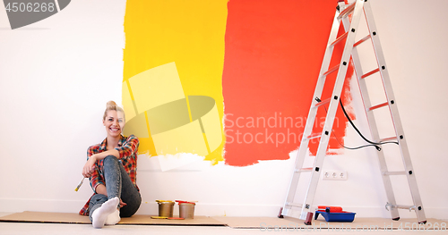 Image of young female painter sitting on floor