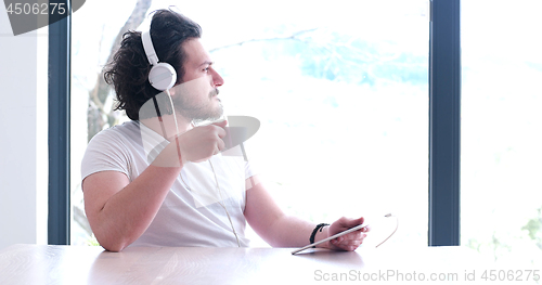 Image of young man listenig music on tablet at home