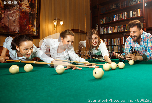 Image of Young men and women playing billiards at office after work.