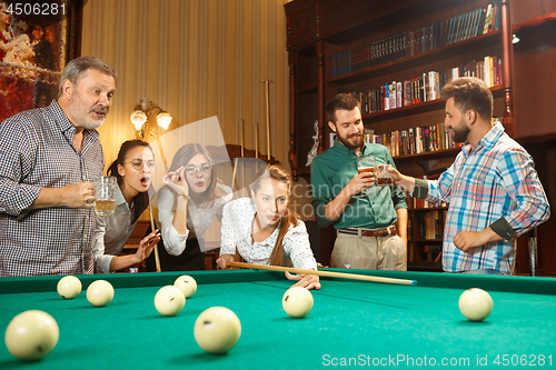 Image of Young men and women playing billiards at office after work.