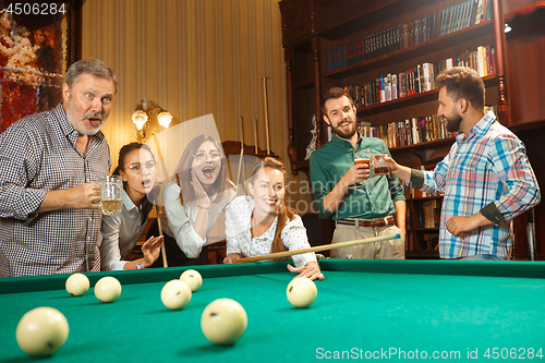 Image of Young men and women playing billiards at office after work.