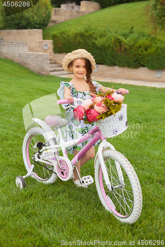 Image of Beautiful little girl riding a bicycle through the park. Nature, lifestyle