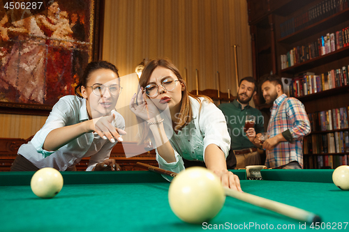 Image of Young men and women playing billiards at office after work.