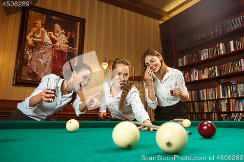 Image of Young women playing billiards at office after work.