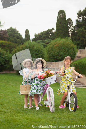 Image of Beautiful little girls riding a bicycle through the park. Nature, lifestyle