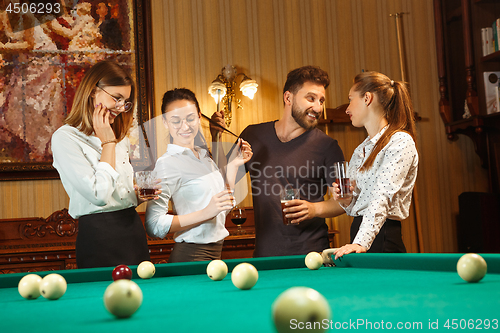 Image of Young men and women playing billiards at office after work.