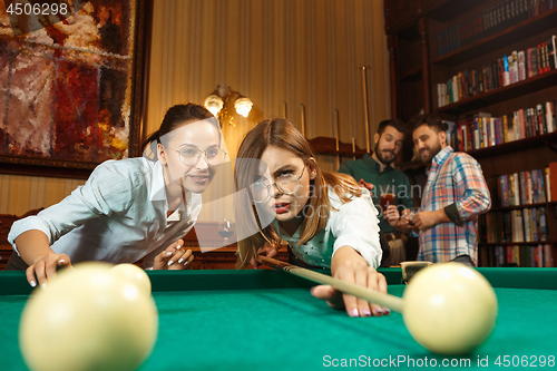 Image of Young men and women playing billiards at office after work.