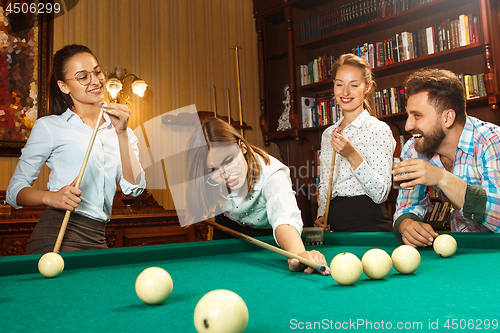 Image of Young men and women playing billiards at office after work.