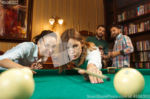 Image of Young men and women playing billiards at office after work.