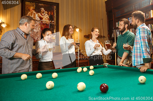 Image of Young men and women playing billiards at office after work.