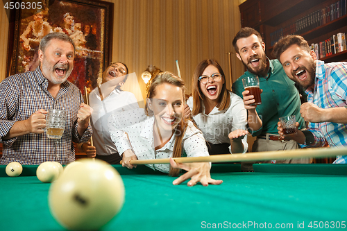 Image of Young men and women playing billiards at office after work.