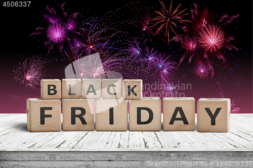 Image of Black friday sign on a wooden table with fireworks