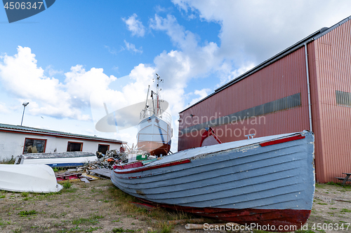 Image of Wooden boat on land with a large ship