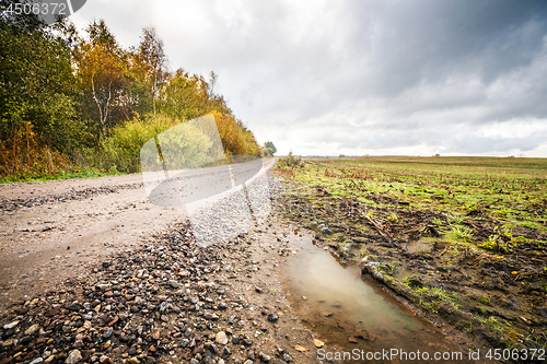 Image of Puddle by a dirt road with small pebbles in the fall