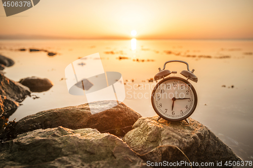 Image of Alarm clock on a rock in the sunrise by the ocean