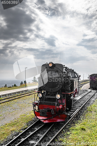 Image of Black locomotive with red color driving on a railtrack