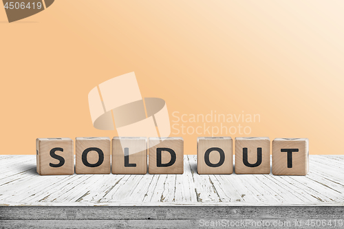 Image of Sold out sign on a wooden table with a yellow wall