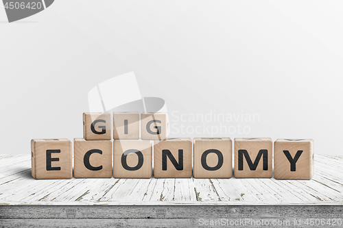 Image of Gig economy sign made of wood on a worn table