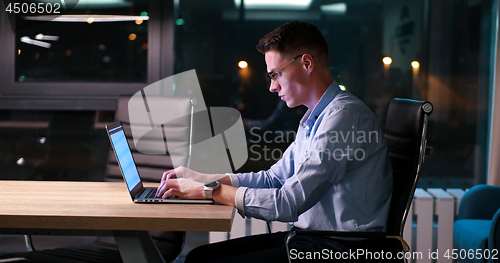 Image of man working on laptop in dark office