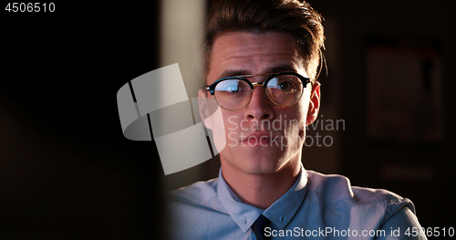 Image of man working on computer in dark office