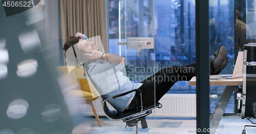 Image of businessman sitting with legs on desk