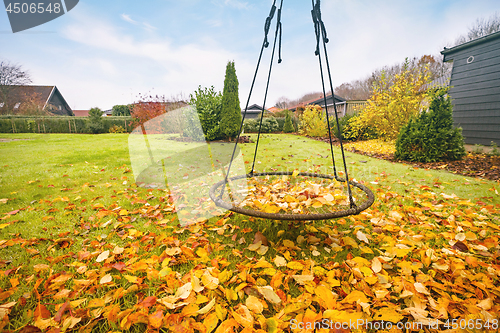 Image of Swing covered with autumn leaves in golden colors