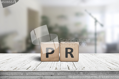 Image of PR sign on a worn table in a bright room