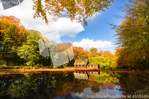 Image of Little red house by a forest lake in the fall