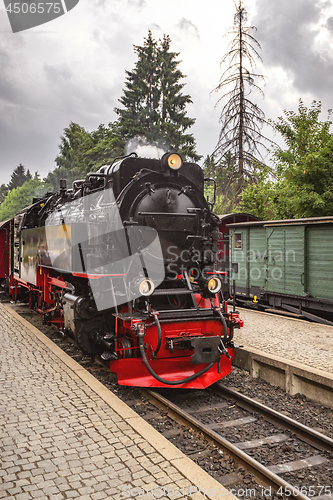 Image of Locomotive arriving at a train station with trees