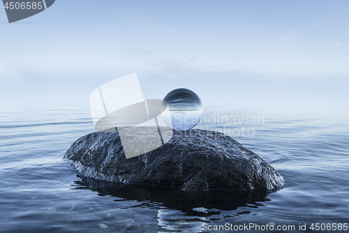 Image of Crystal orb on a black rock by the blue ocean