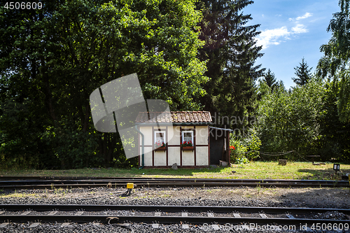 Image of Small house close to a railroad with red flowers