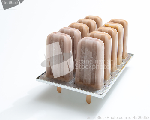 Image of Cold chocolate dessert on a stick in plastic form on a white bac