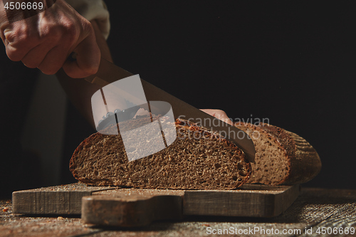 Image of Men\'s hands cut fresh homemade bread