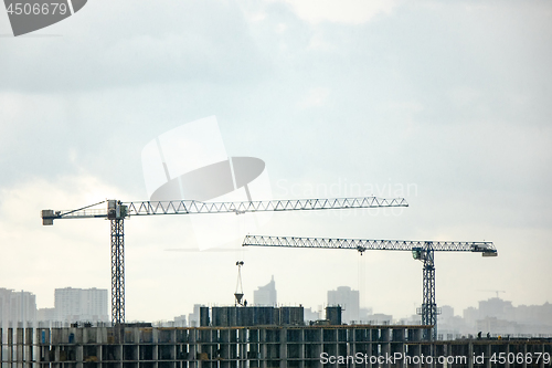 Image of Industrial landscape with silhouettes of cranes on the gray cloudy background.