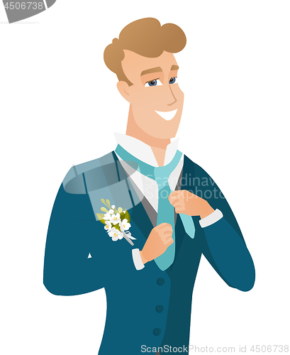 Image of Young caucasian cheerful groom adjusting tie.